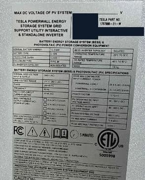Actual Powerwall label showing Tesla part number 1707000-21-M. Serial number and QR code permanently blacked out.